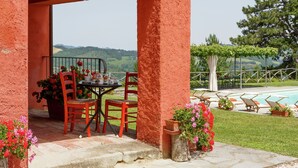 An outdoor seating area with a table and chairs, a pool, and a view of the hills. - Villa with private swimming pool (Tredozio)
