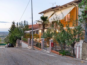 A residential property with a paved driveway, a covered patio, and a view of the countryside.