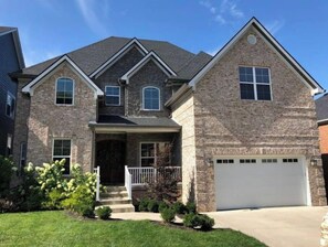 Stunning two-story home with a brick and stucco exterior, gabled roof, and central entryway.