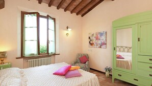 Ein Schlafzimmer mit Bett, Stuhl, Kommode, Heizkörper, Fenster und einem Bild an der Wand.