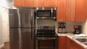 A kitchen with stainless steel appliances, including a refrigerator, microwave, oven, and coffee maker. - Restored 1920's peaceful, lakeside cottage (Pullman)