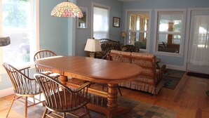 A dining area with a wooden table and chairs, a patterned sofa, and a hanging lamp. - Restored 1920's peaceful, lakeside cottage (Pullman)