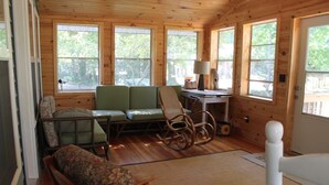 A cozy cabin interior with a green sofa, rocking chair, and a small table with a lamp. - Restored 1920's peaceful, lakeside cottage (Pullman)