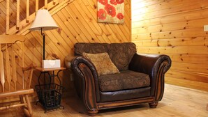 Un interior de madera con un sofá de cuero, una lámpara y un cuadro de flores rojas.