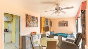 A compact living space with a dining area, a sofa, a ceiling fan, and a kitchen area with a refrigerator and a microwave. - Saint Raphael plage Peguiere (Saint Raphäel)