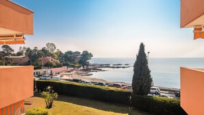 A coastal view from a balcony overlooking a beach with parked cars and a clear sky. - Saint Raphael plage Peguiere (Saint Raphäel)