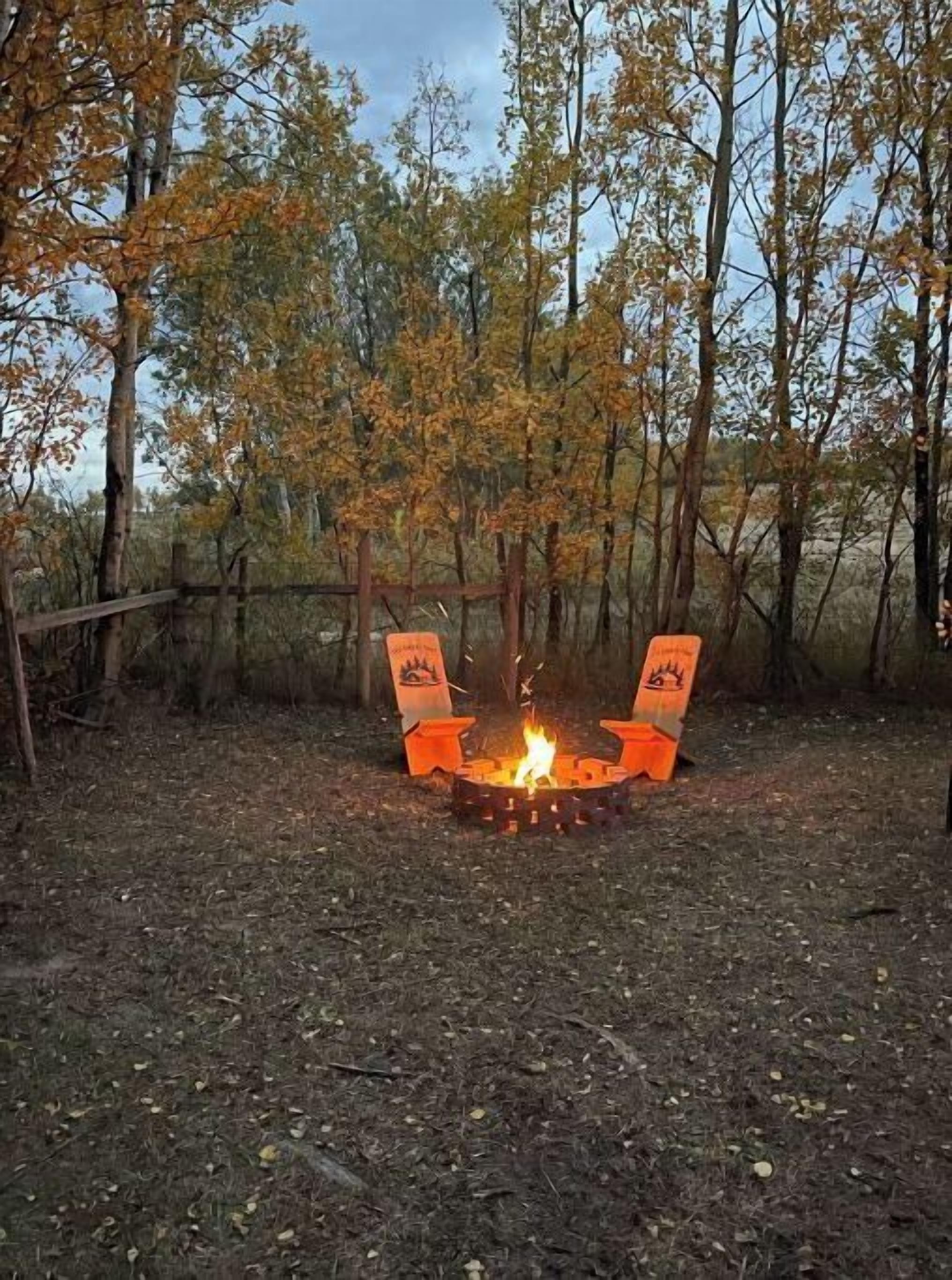 A campfire in a wooded area with trees in the background.