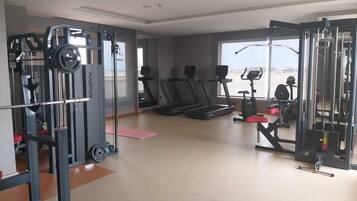 Un gimnasio con máquinas de cardio, equipo de levantamiento de pesas y un ventanal con vistas.