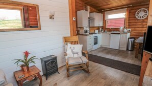 A cozy cabin interior with a wooden interior, a dining area, a kitchen with white cabinets, and a fireplace. - Ingram (Morpeth)