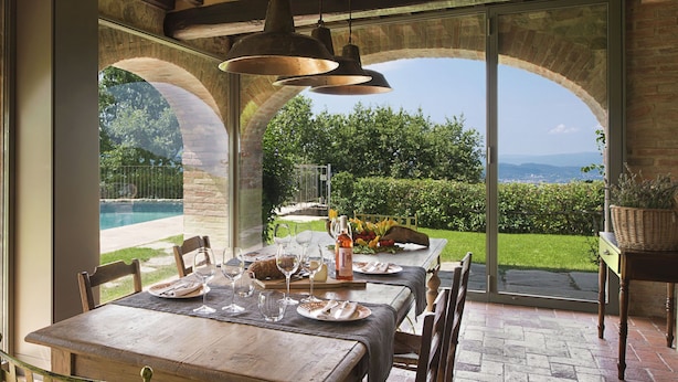 An outdoor dining area with a table set for two, overlooking a pool and garden. - Villa with Pool and Wine Country Charm (Arezzo)