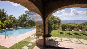 A pool area with a view of a cityscape through an arched window. - Villa with Pool and Wine Country Charm (Arezzo)