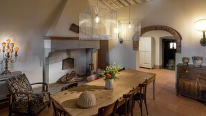A rustic dining area with a wooden table, chairs, and a hanging light fixture.