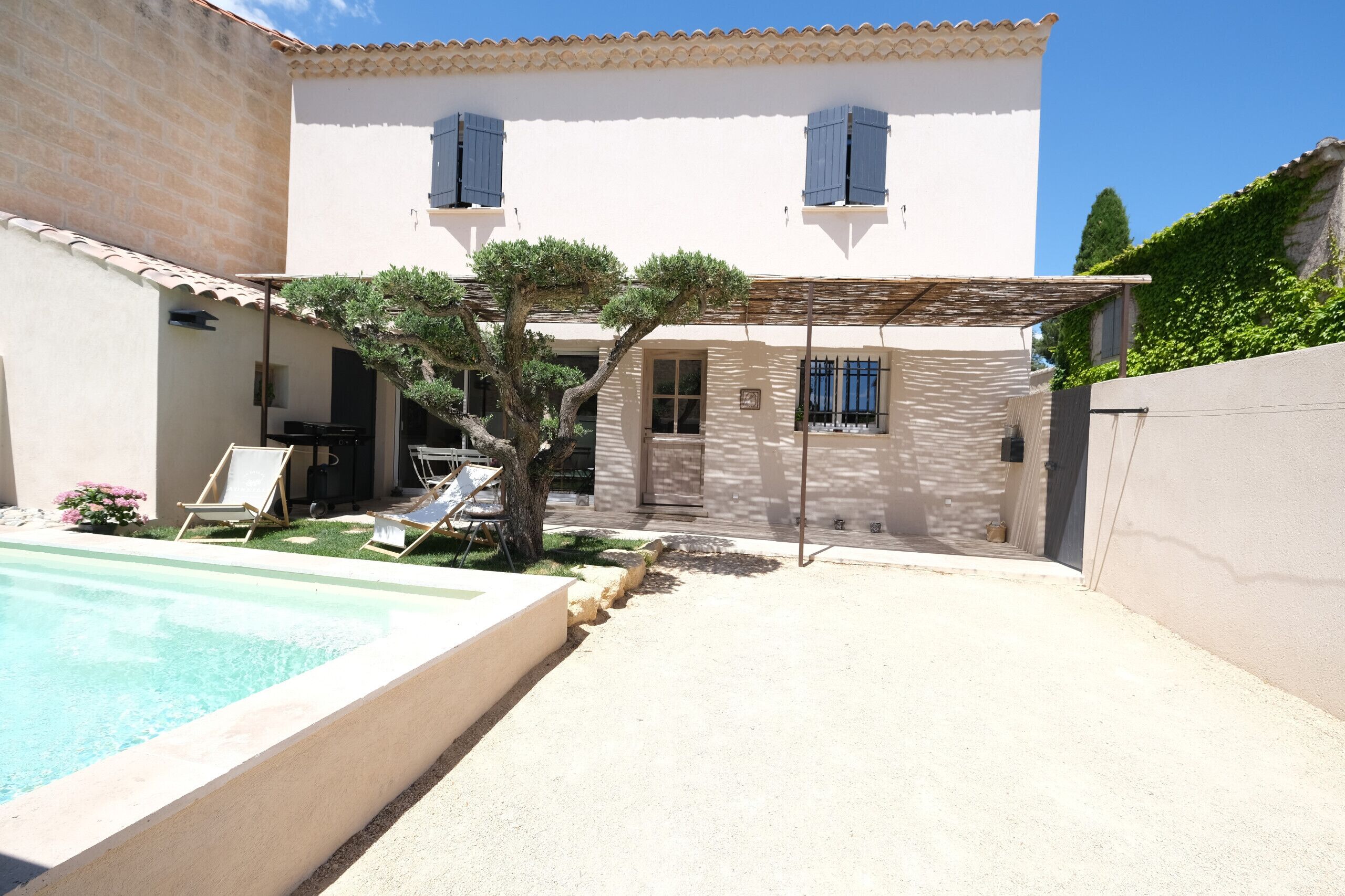 Una casa de dos pisos con piscina, un patio cubierto y un pequeño jardín.