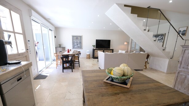 A modern living room with a wooden table, a sofa, and a staircase.
