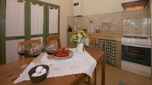 Una cocina acogedora con una mesa de madera preparada para comer, una estufa y un salpicadero de azulejos.