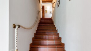 Eine Treppe mit Geländer am oberen Ende, die zu einer Empfangsebene mit gerahmten Bildern führt.
