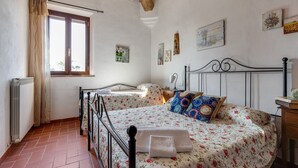 Een slaapkamer met twee bedden, een raam met gordijnen, een radiator en een houten plafond.