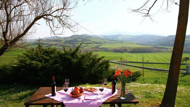 A picnic table set on a grassy area with a scenic view of rolling hills and a distant castle.