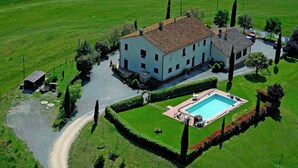 A large white building with a tiled roof, surrounded by well-maintained lawns and a swimming pool.