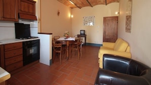 A compact kitchen with wooden cabinets, a stove, and a dining area with a table and chairs.