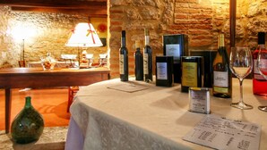 Mesa dispuesta con botellas de vino, copas y un menú en una habitación con paredes de piedra y una lámpara.