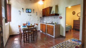 Una cocina compacta con armarios de madera, salpicadero de azulejos y una zona de comedor con mesa y sillas.