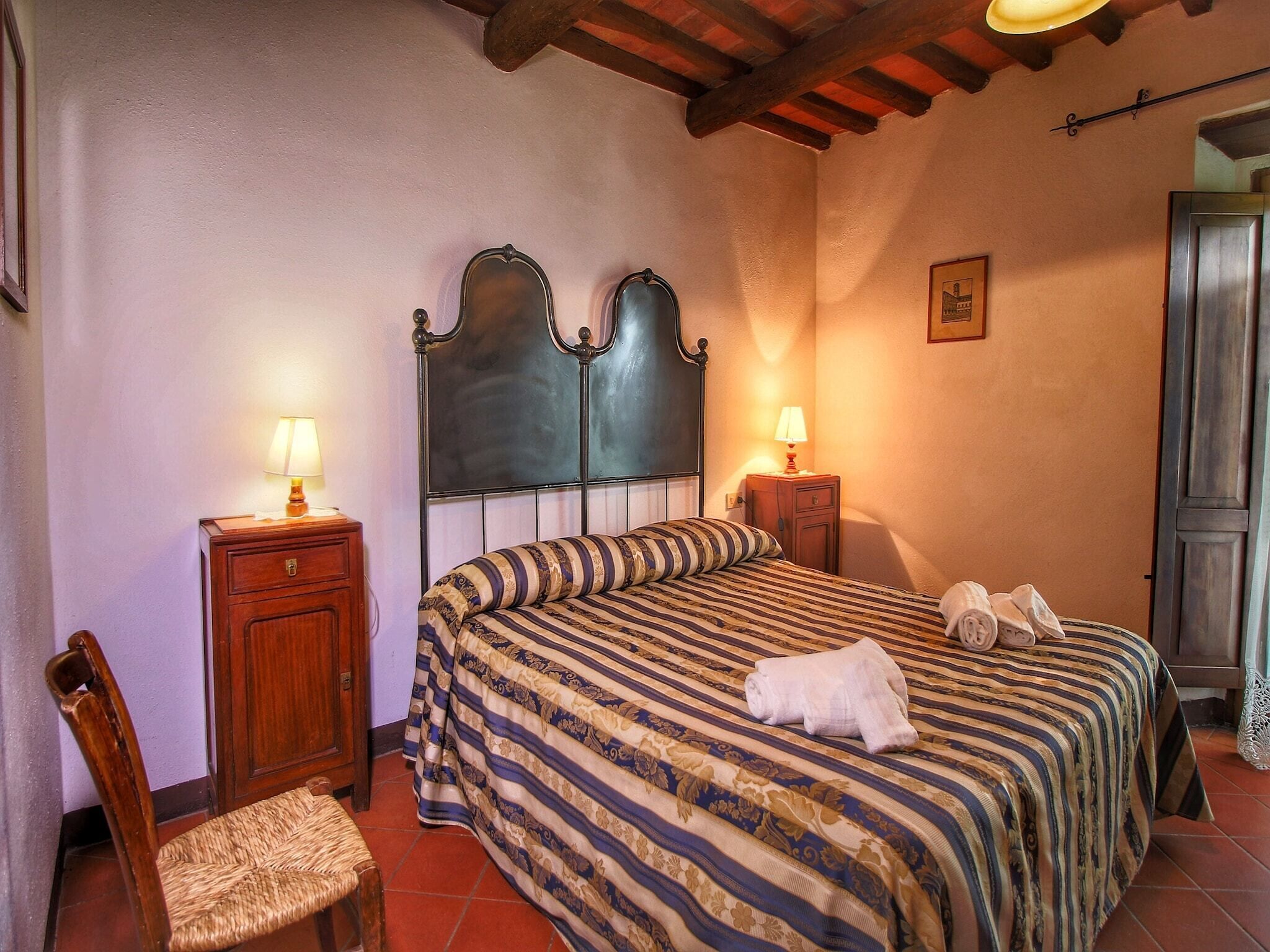 Une chambre à coucher comprenant un lit, deux tables de chevet, une chaise et un banc en bois.
