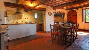 Una cocina rústica con techo de madera, salpicadero de azulejos y un comedor con mesa y sillas de madera.