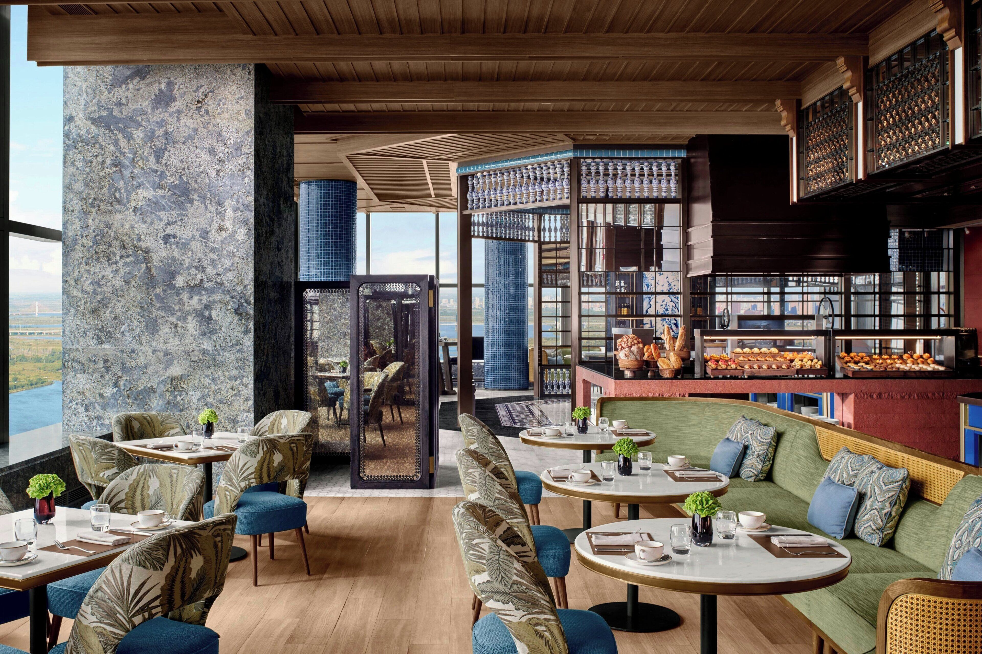 Un restaurante moderno con vistas, con mesas redondas, asientos cómodos y diversas opciones de comida.