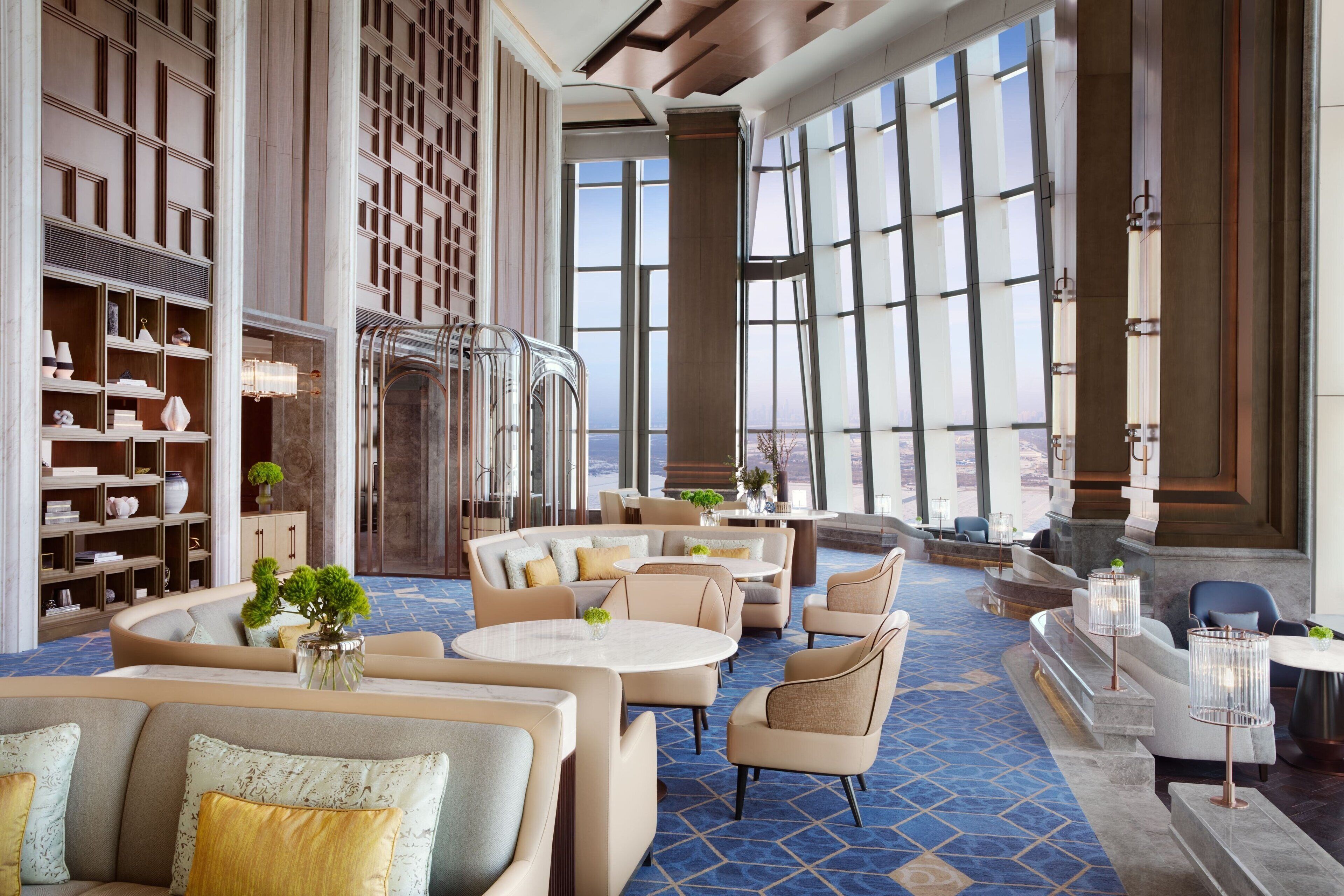 A spacious lobby with seating areas, a large window offering a view, and a decorative wall with shelves.