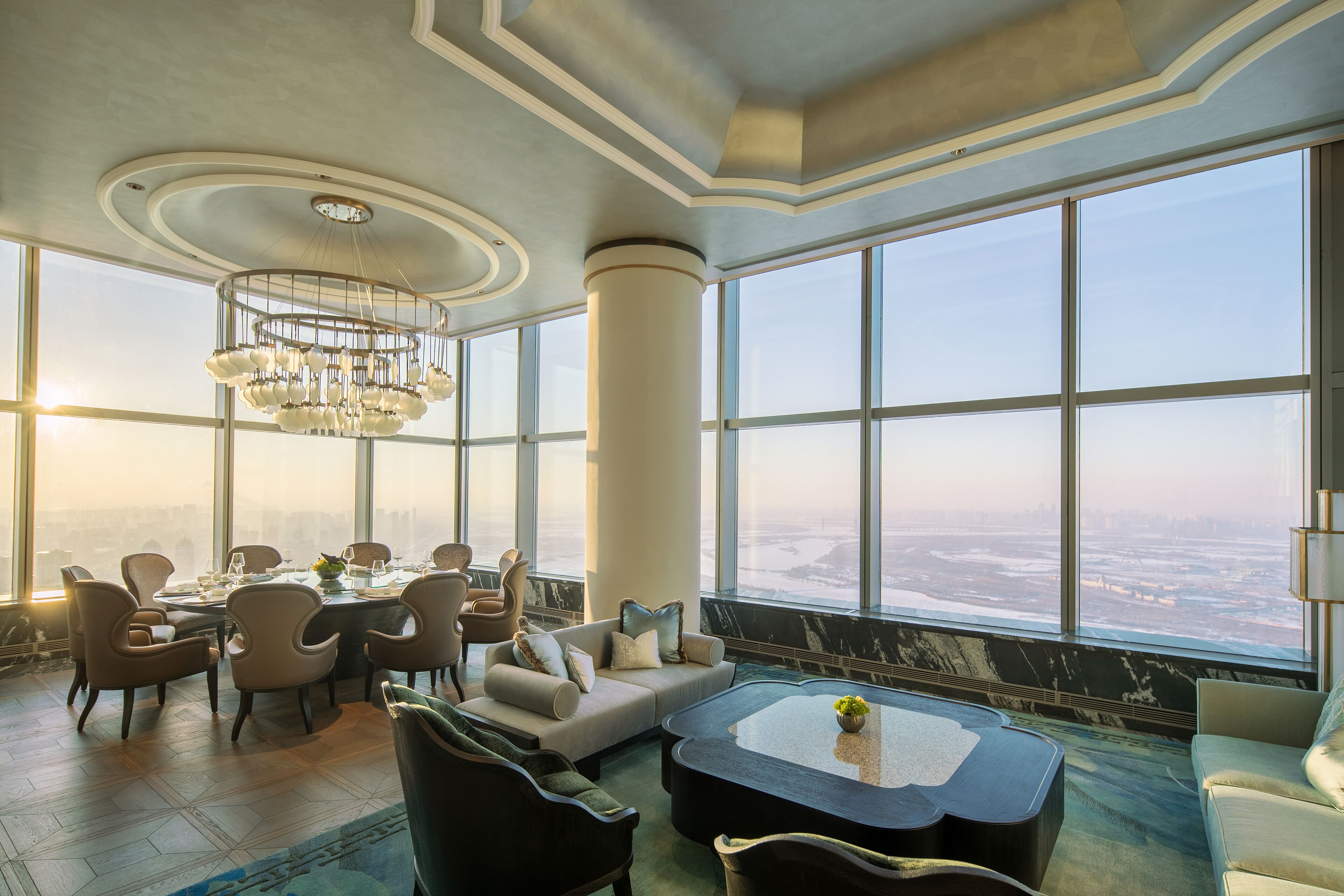 A spacious room with a large dining table, comfortable seating, and a view of a cityscape through large windows.