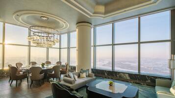 A spacious room with a large dining table, comfortable seating, and a view of a cityscape through large windows.
