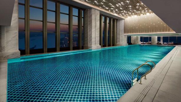 Une piscine intérieure moderne avec vue sur la ville, de grandes fenêtres et un design contemporain au niveau du plafond.