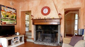 Una sala de estar con chimenea, televisor y un cuadro en la pared.