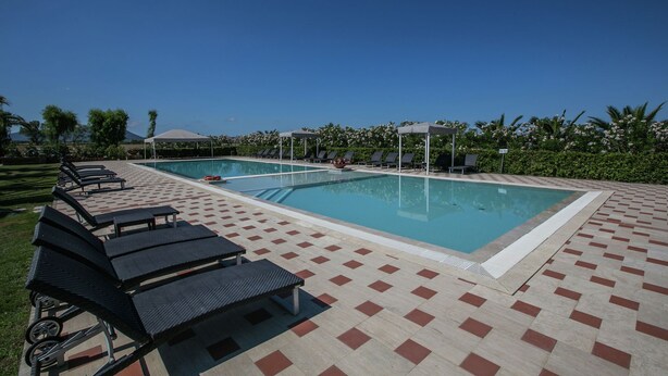 A pool area with two pools, lounge chairs, and a tiled deck.