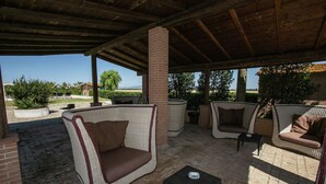An outdoor patio with wicker furniture, including a sofa and chairs, a small table, and a brick floor.