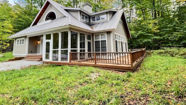 Ein Haus mit einer großen Veranda, einem überdachten Eingangsbereich und einer Terrasse.