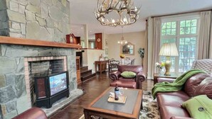 Ein Wohnzimmer mit Kamin aus Stein, Ledersofas, einem Couchtisch und einer Chandelier.