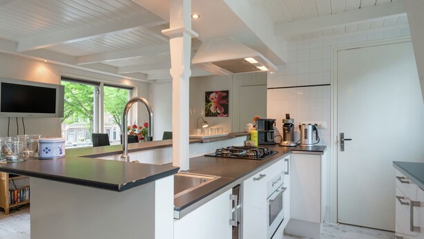 A modern kitchen with a central island, built-in appliances, and a large window providing natural light. - Elegant Apartment in Hoorn with Roof Terrace (Hoorn)