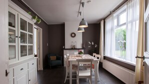 Zona pranzo con tavolo bianco, sedie e lampadario.