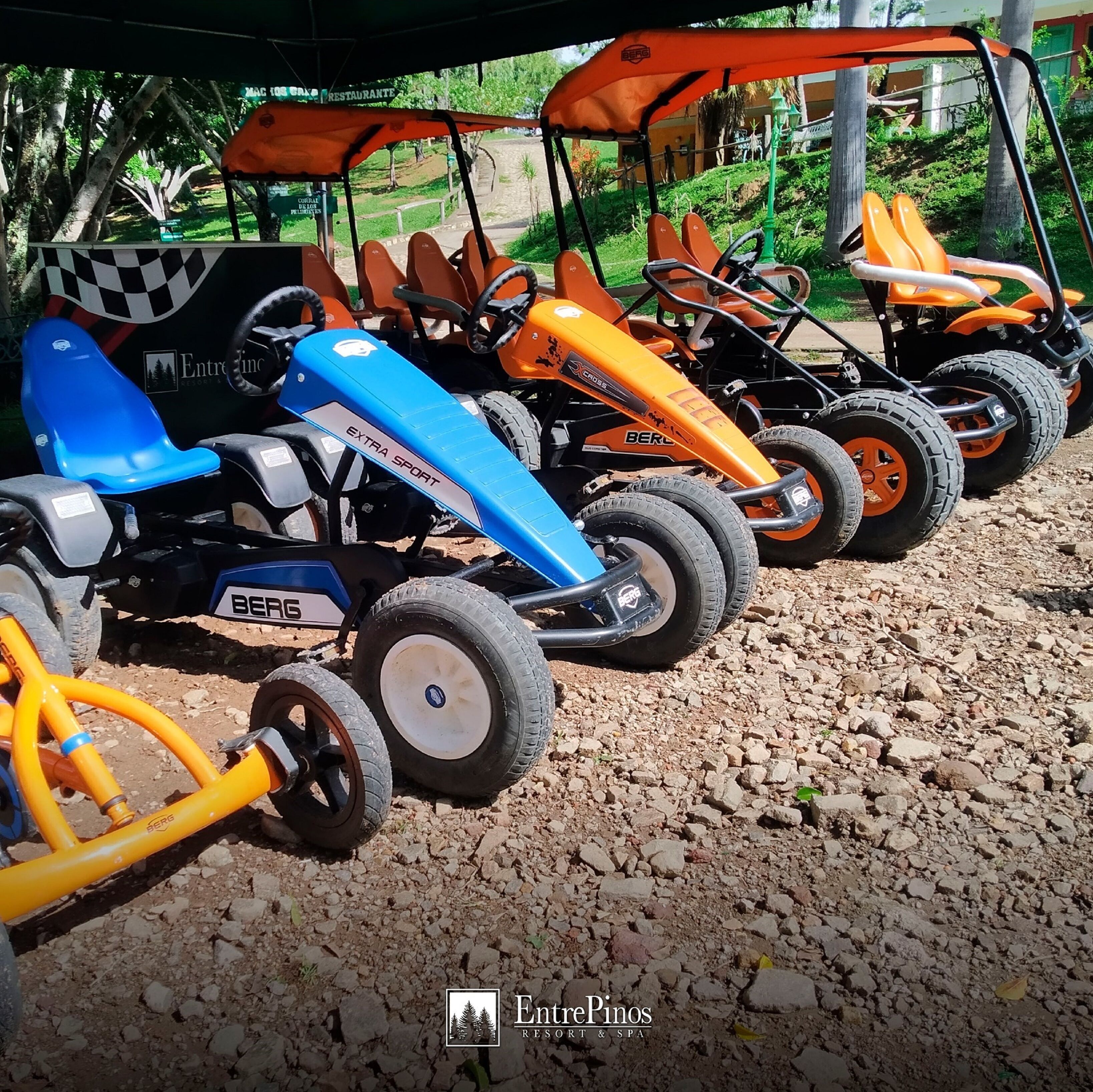 A row of go-karts parked on a gravel surface.