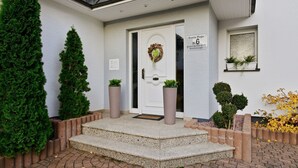 A building entrance with a white door, a sign reading "Familie Finger", and a small window with plants. - Wohnung in Madfeld nahe Willingen Skilift (Brilon-Madfeld)