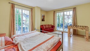 A bedroom with a bed, a red sofa, a foosball table, and large windows. - Wohnung in Madfeld nahe Willingen Skilift (Brilon-Madfeld)