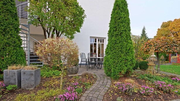A garden pathway leading to a seating area with a white building in the background. - Wohnung in Madfeld nahe Willingen Skilift (Brilon-Madfeld)
