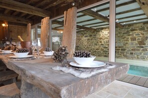 A rustic wooden table set for a meal with a stone wall and pool in the background. - Country Home in Theux with Pool & Sauna (Theux)