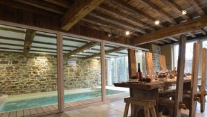 Un intérieur rustique avec un mur en pierre, un plafond en bois et un jacuzzi entouré de parois en verre.