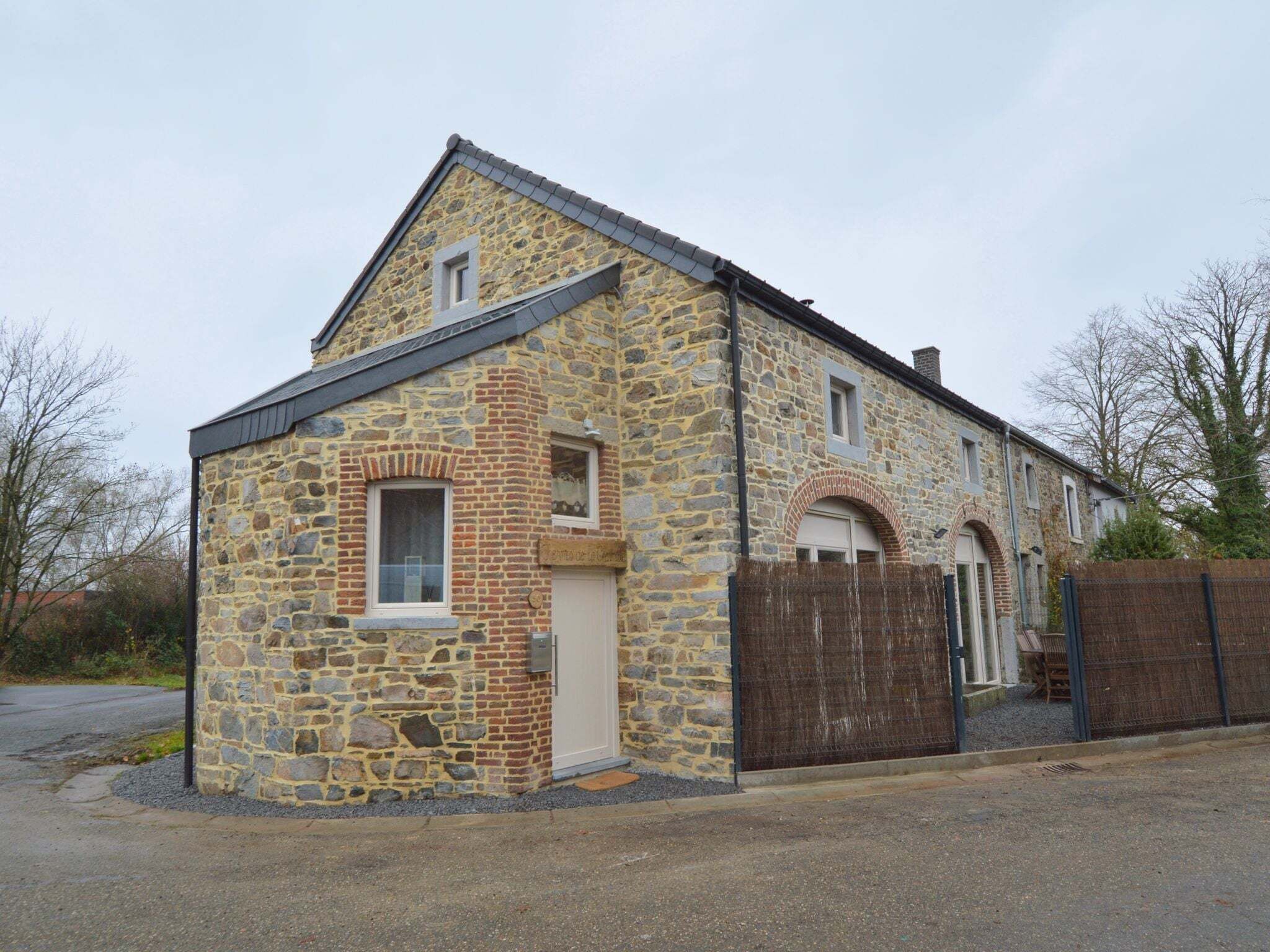 A stone building with a gabled roof, a small window, and a door.