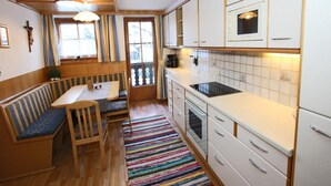 A compact kitchen with a dining area, wooden bench, and a colorful striped rug. - Apartment in Kaltenbach near Ski Lift (Kaltenbach)
