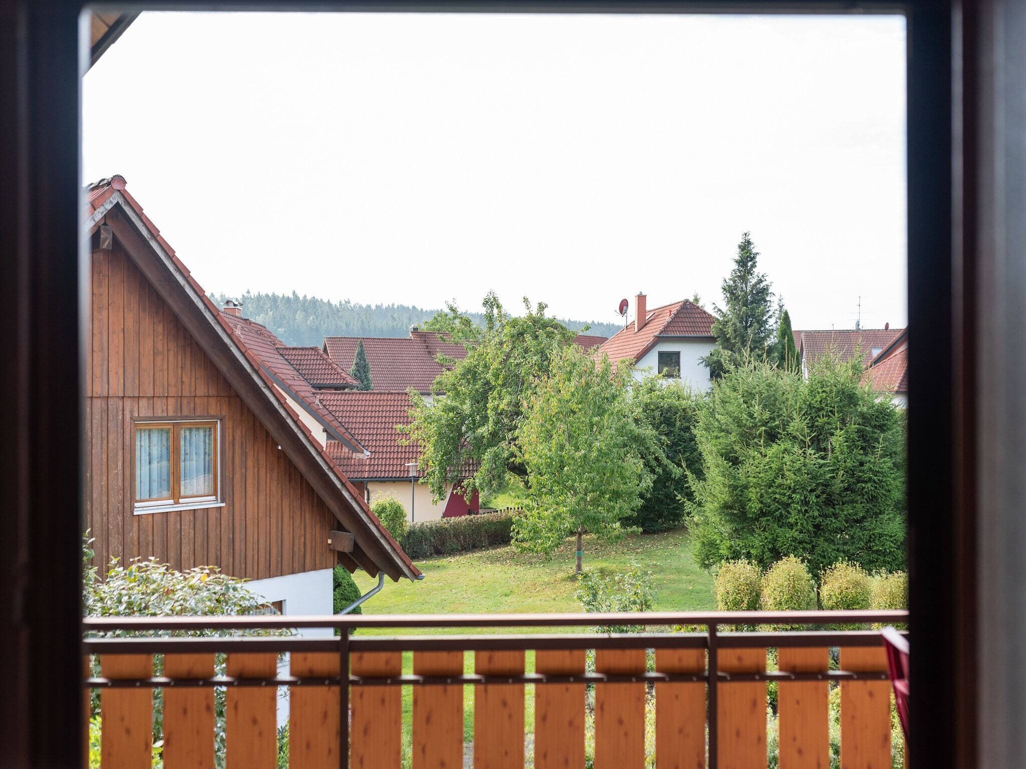 Vista de una zona residencial con casas, una valla de madera y un jardín cubierto de césped.