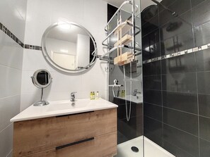 A modern bathroom with a wooden vanity, a round mirror, a glass shower enclosure, and black tiled walls. - N&J - FLORIDA BEACH - Very close sea - Balcony (Niza)